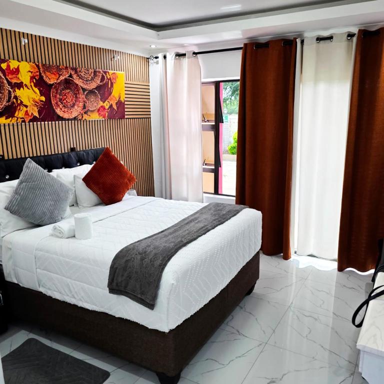 a bedroom with a large bed and a large window at Rest & Digest in Serowe