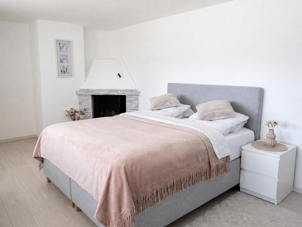 a white bedroom with a bed and a fireplace at D&C Norway in Kristiansand