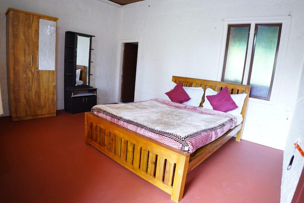 a bedroom with a wooden bed with red pillows at Private Cottage Room Non AC in Ponnampet