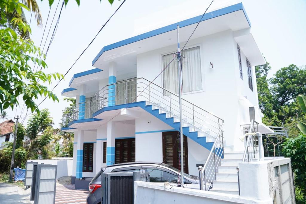 a white house with blue accents at Twilight Stays Cherai Beach in Pallipuram