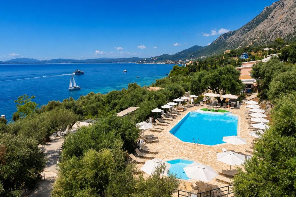 a resort with a pool and umbrellas and a boat at Nissaki Sea View Hotel in Corfu