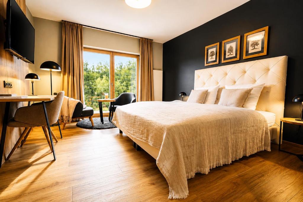 a hotel room with a bed and a desk and a window at 2tHEIMAT - Hotel & Restaurant in Morbach