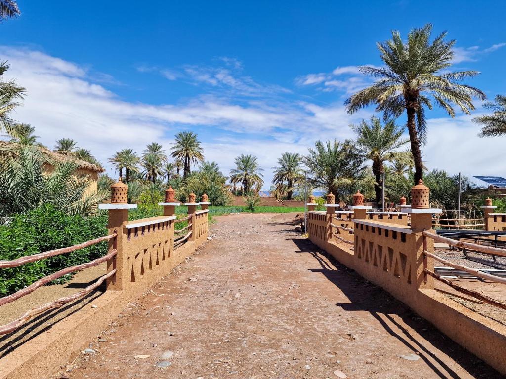 a bridge over a dirt road with palm trees at Taragalte Park - Motorhomes in Zagora