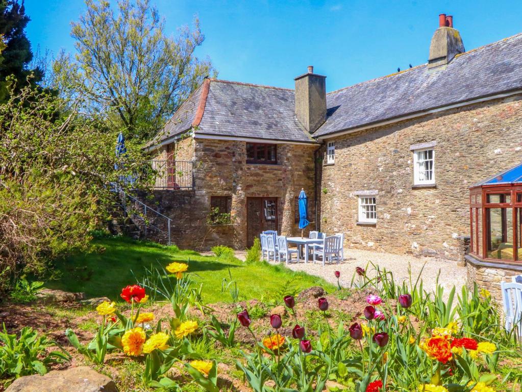 an old stone house with flowers in the garden at East Bickleigh in Totnes