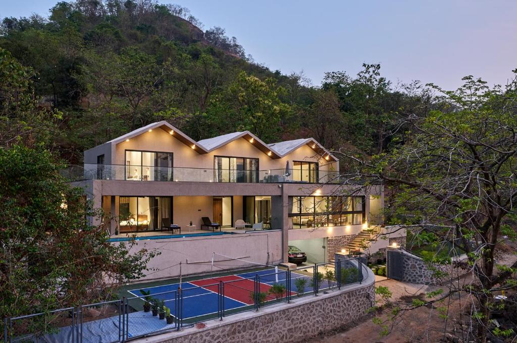 a house with a swimming pool in front of it at SaffronStays Pickle & Play in Khandāla