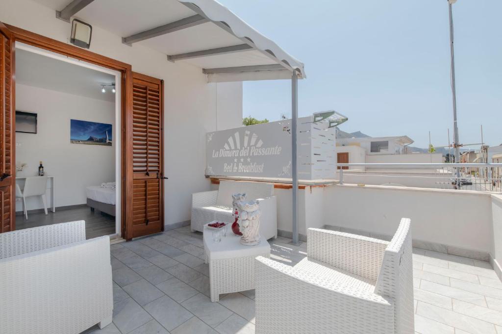 a patio with white chairs and a sign on a building at La Dimora del Passante in San Vito lo Capo