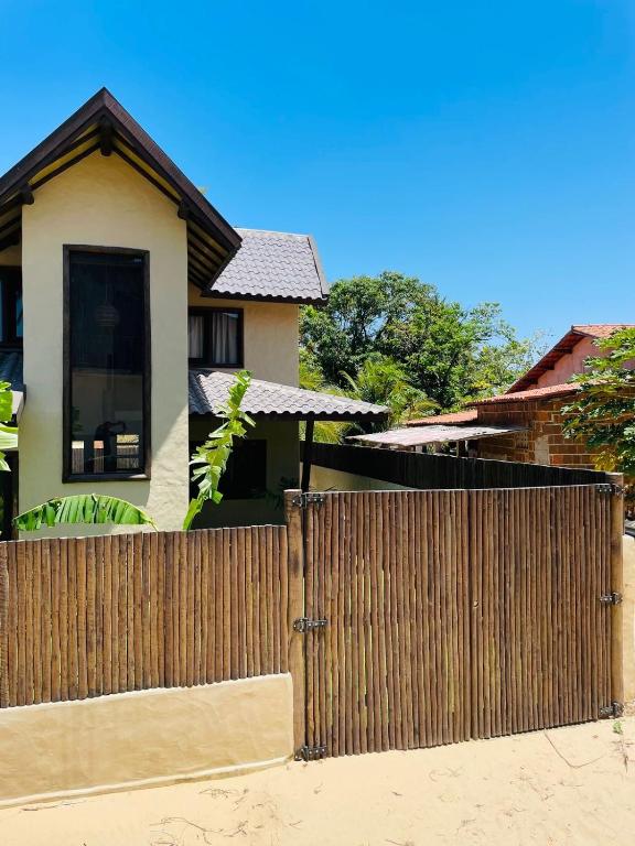a wooden fence in front of a house at Villa Coco e Sol - Casa com Jacuzzi in Amontada