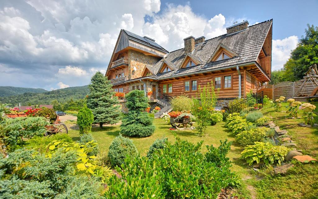 a large wooden house with a garden in front of it at Pokoje Gościnne u Laskowskich in Smerek