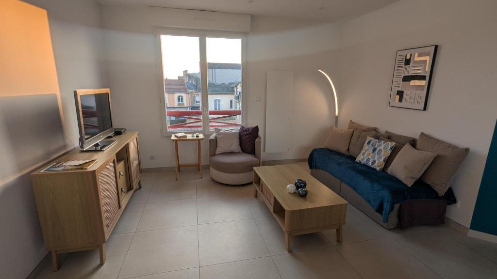 a living room with a blue couch and a tv at Cocon moderne avec terrasse a deux pas de locean in Saint-Brevin-les-Pins