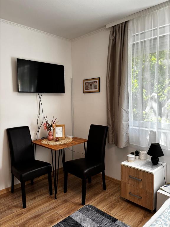 a living room with a table and two chairs and a television at Studio Apartman M&S Apatin in Apatin
