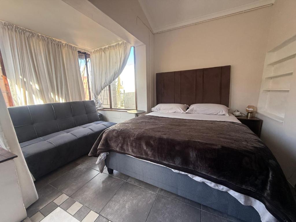 a bedroom with a large bed and a couch at Suite Dreams Cute Studio Flat in Panorama