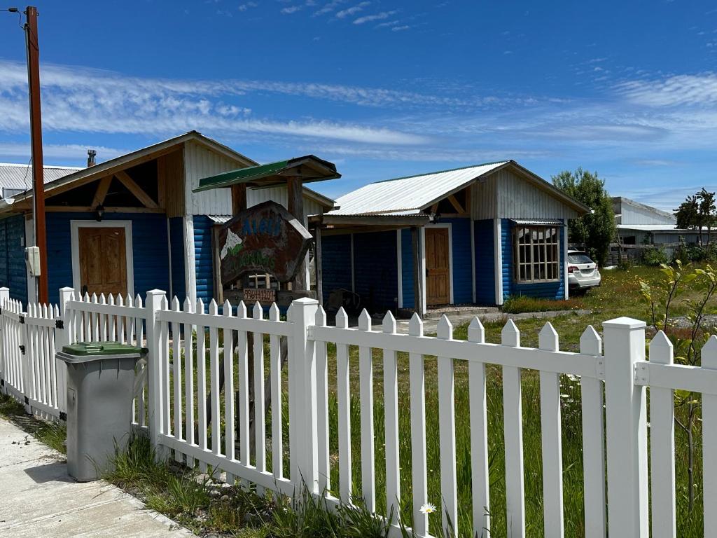 a white fence in front of a blue house at Cabañas Alelí in Chaitén