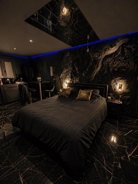 a bedroom with a bed with a rock wall at Obsidian Suite Love Room in Triel-sur-Seine