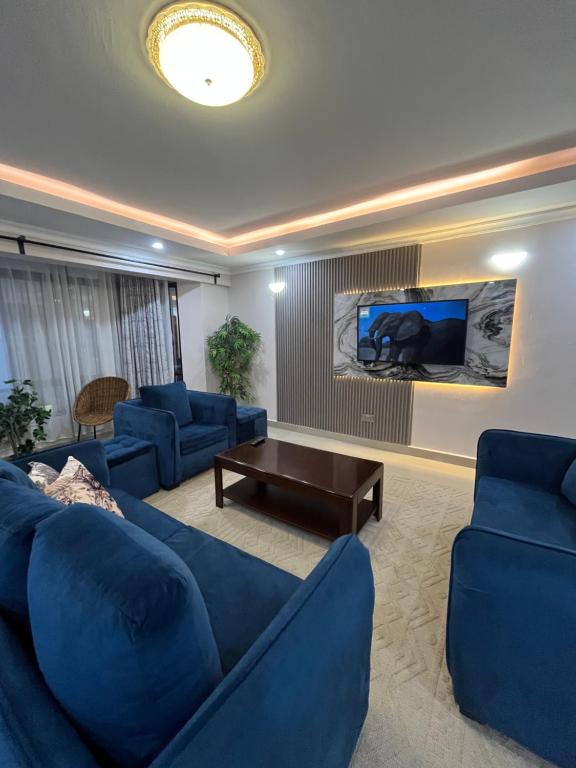 a living room with blue couches and a table at Lakeview 3Bedroom Condo with heated pool in Nakuru Town in Nakuru