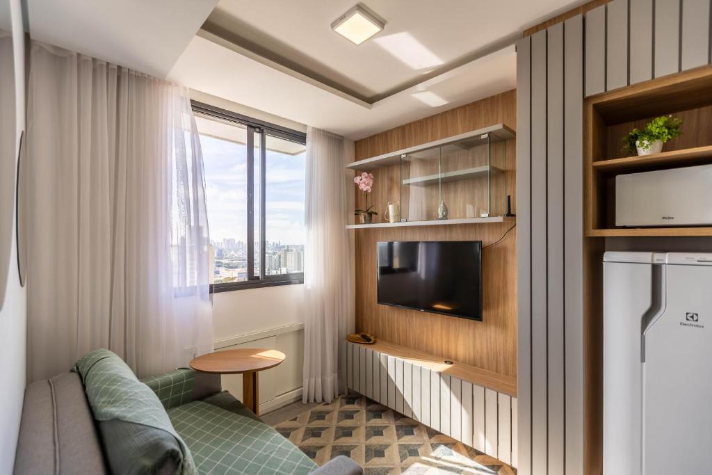 a living room with a couch and a tv in a room at Apartamento ensolarado em condomínio clube in Curitiba