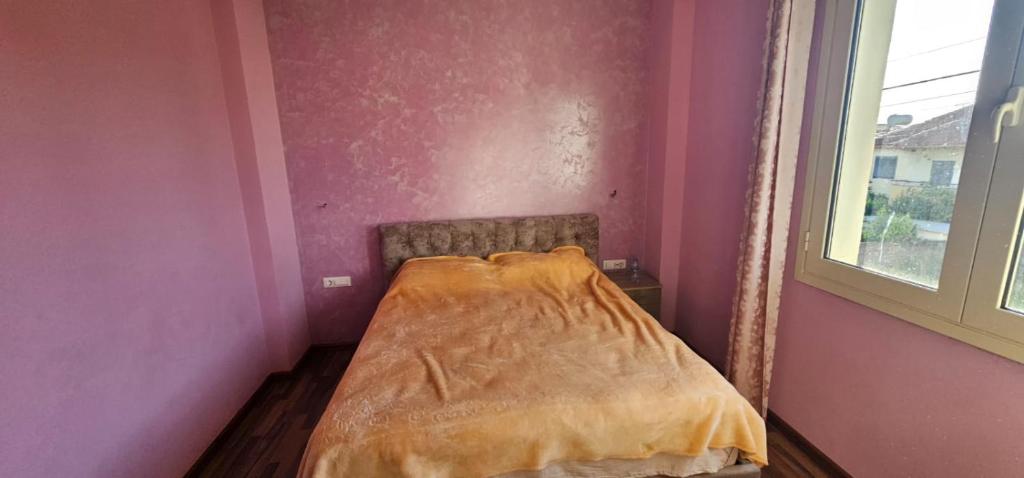 a bed in a pink room next to a window at Villa Doda in Durrës
