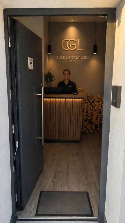 a woman sitting at the counter of a golden grizzlyly lobby at Golden Grey Loft Bahrenfeld Volkspark Hamburg in Hamburg