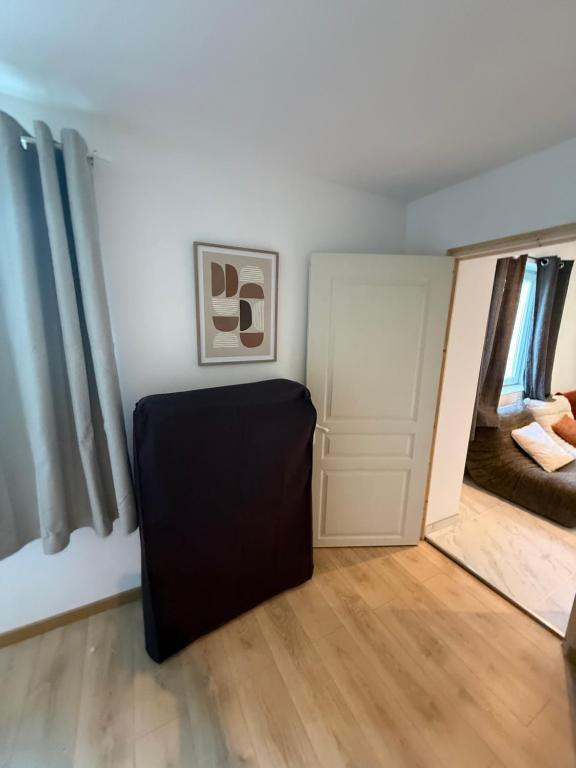 a room with a black ottoman in front of a door at La Clef des Champs in Mecquignies
