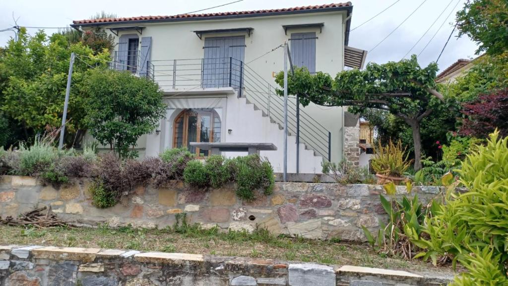 a white house with a stone retaining wall at The Arch House in Kymi