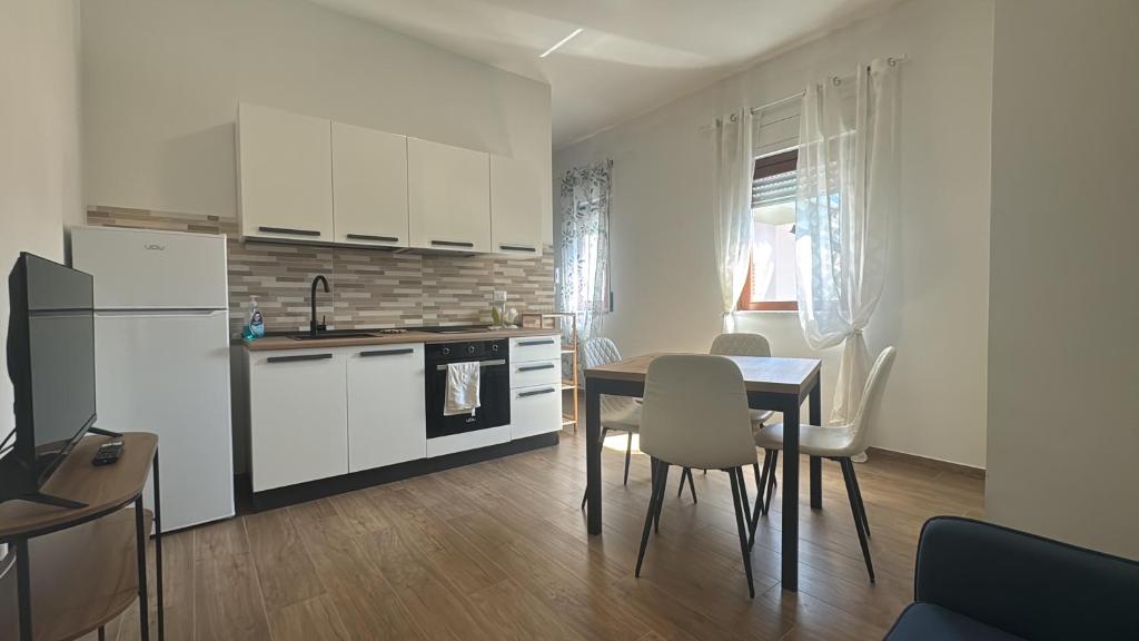 a kitchen with white cabinets and a table and chairs at PiTer House - Luxury Apartments & Private Parking in Lusciano