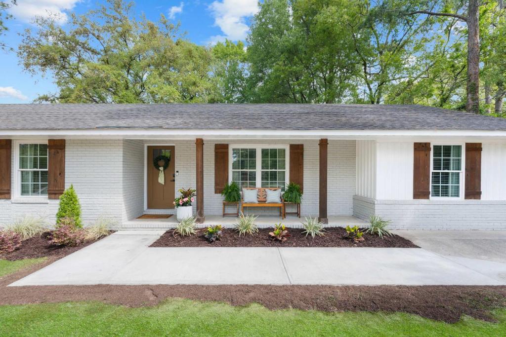 a white house with a bench in the front yard at GSU Getaway 4BR3BA spacious pet friendly in Statesboro