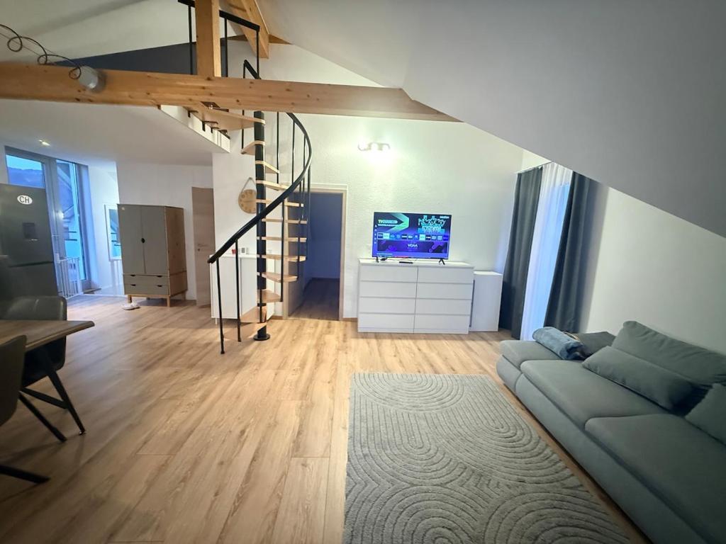 a living room with a couch and a tv at GalerieLoft Winterzeit Thunersee&Mountainview in Thun
