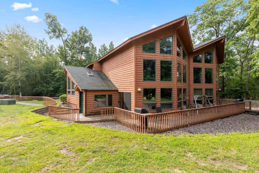 a log home with a large deck on a lawn at Causeway On Gull - 2 Bedroom in Nisswa