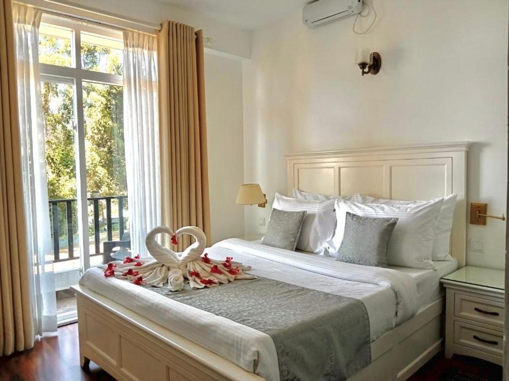 a bedroom with a large white bed with a window at THE WIND LILY - Lake View Luxury Apartment in Nuwara Eliya