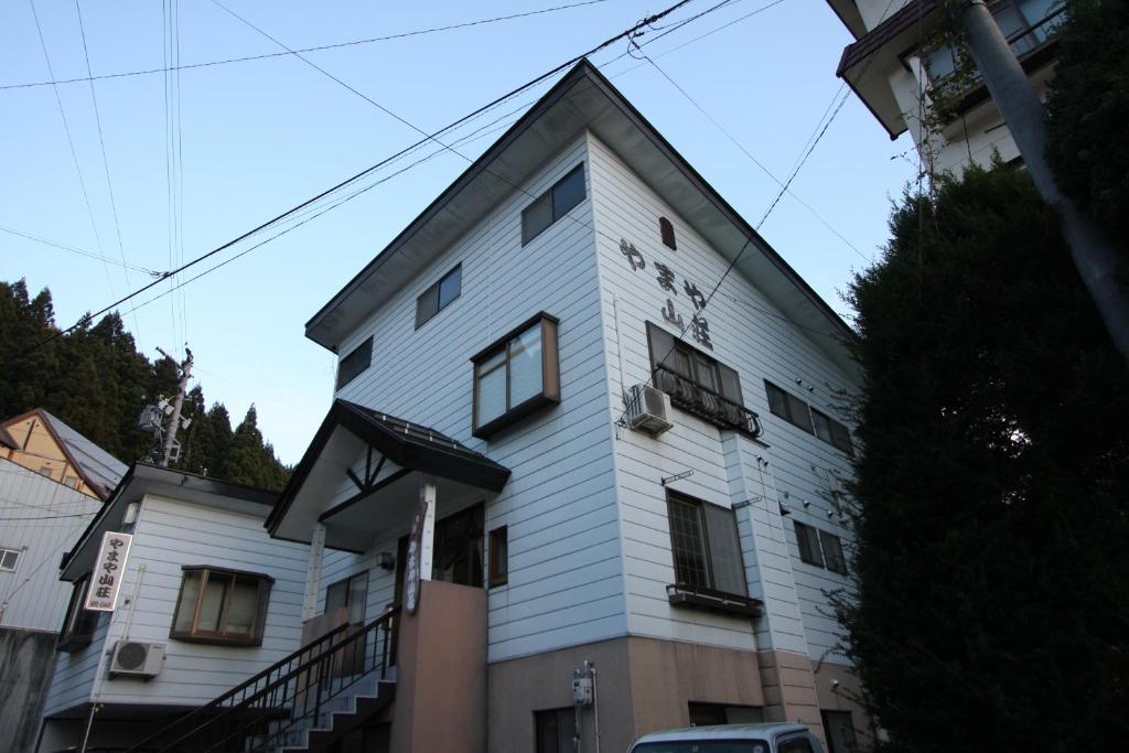 biały budynek z oknami i schodami w obiekcie Nozawaonsen Yamayasanso w mieście Nozawa Onsen