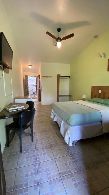 a bedroom with a bed and a desk and a television at Pousada Cantarel in Maricá