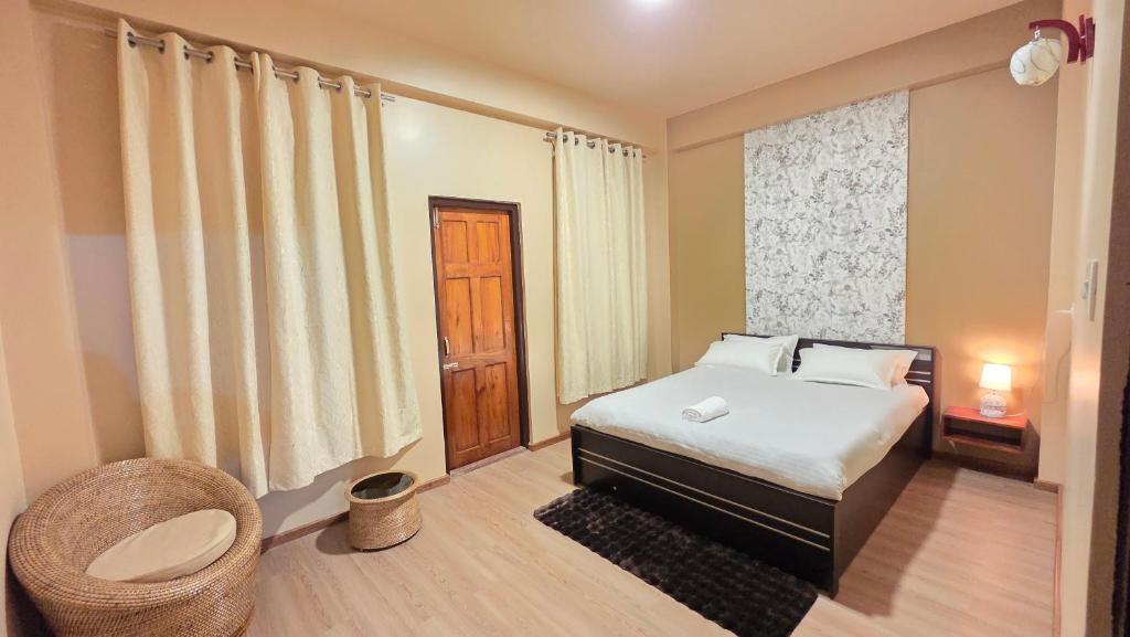 a bedroom with a bed and a chair and a window at Celeste Inn in Shillong