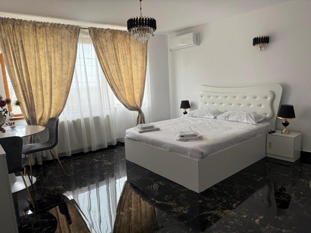a bedroom with a white bed and a table and a window at Vila Dari in Tulcea