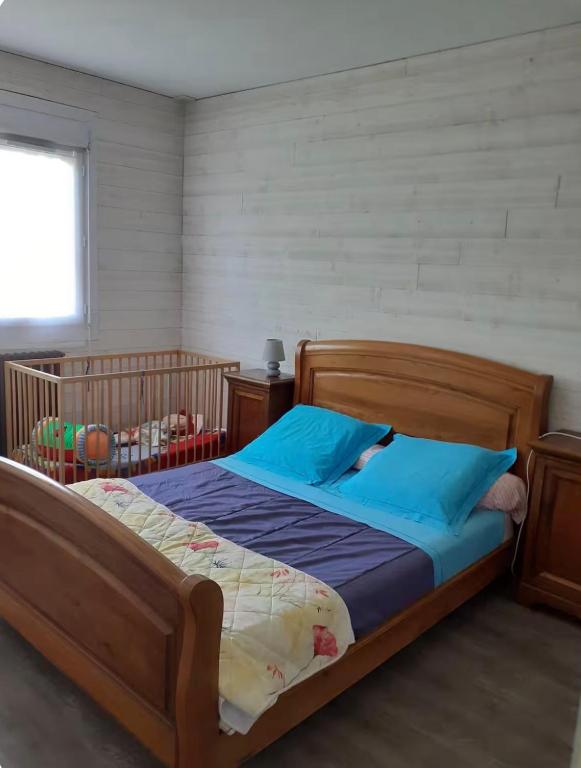 a bedroom with a wooden bed with blue pillows at Maison Treize vents in Treize-Vents
