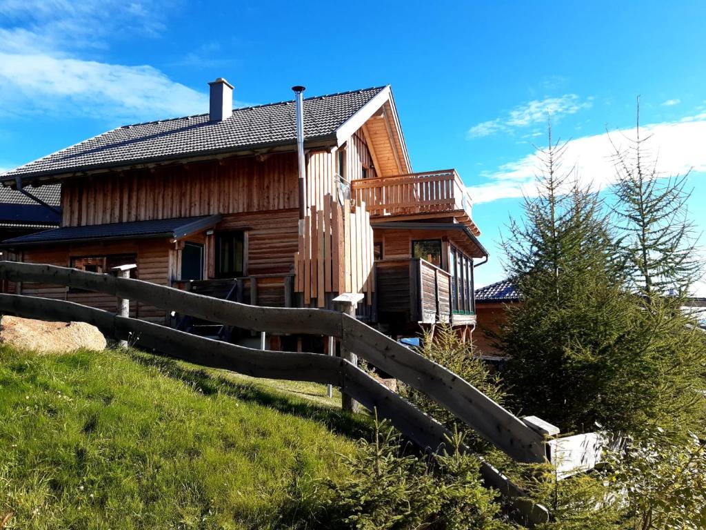 a wooden house with a fence in front of it at Wellnesshütte Klippitztörl in Klippitztorl