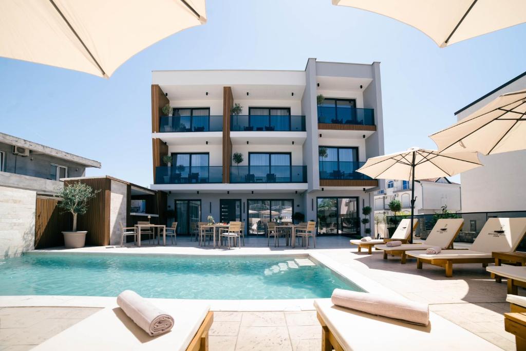 an apartment building with a swimming pool with chairs and umbrellas at Boutique Hotel Zara in Ulcinj