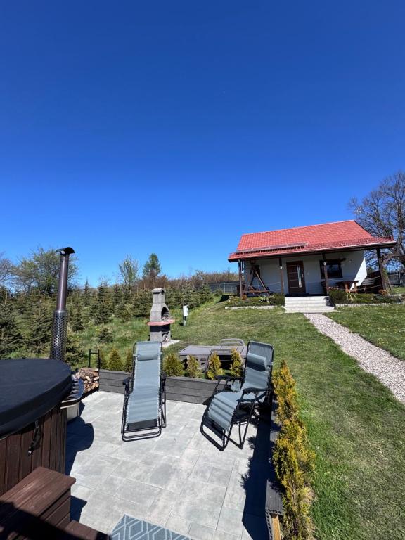a patio with chairs and a grill and a house at Domek na wzgórzu in Ukta