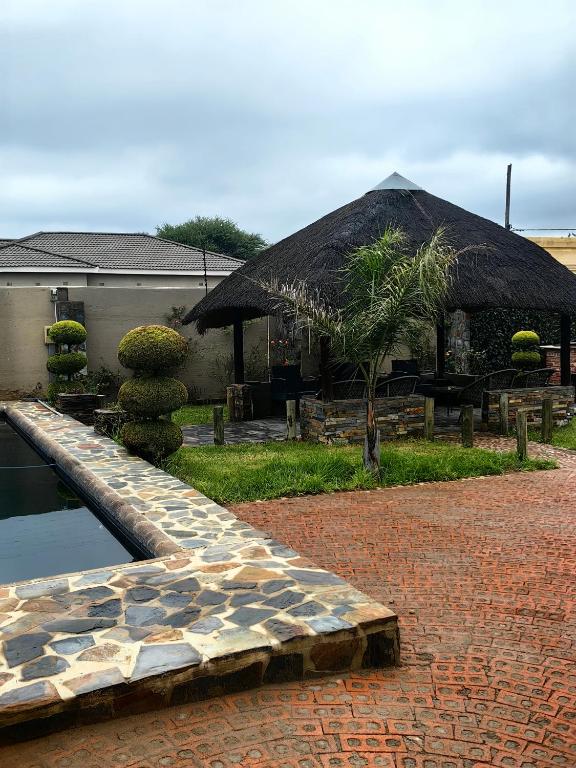 a building with a large straw umbrella next to a pond at Mukani B&B in Lobatse