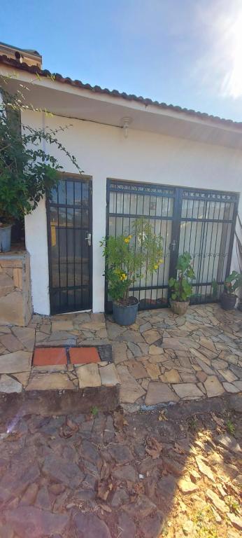 a white house with a gate and some plants at Contos de Alice Quartos in Tiradentes