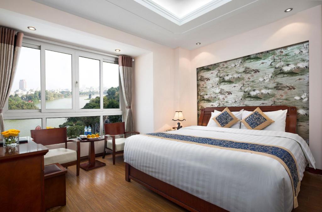 a bedroom with a large bed and a large window at Lakeside Palace Hotel in Hanoi