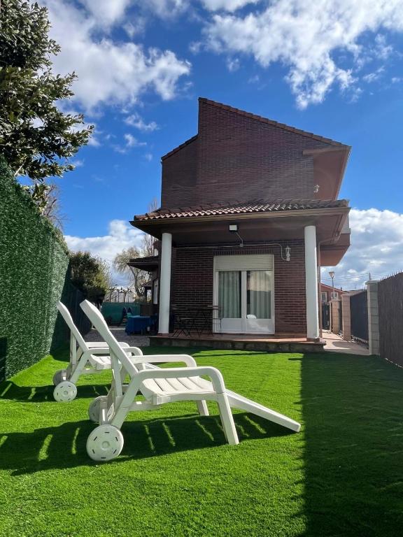 two white chairs sitting in the grass in front of a house at Las Candelas, Casa Turística in Uruñuela
