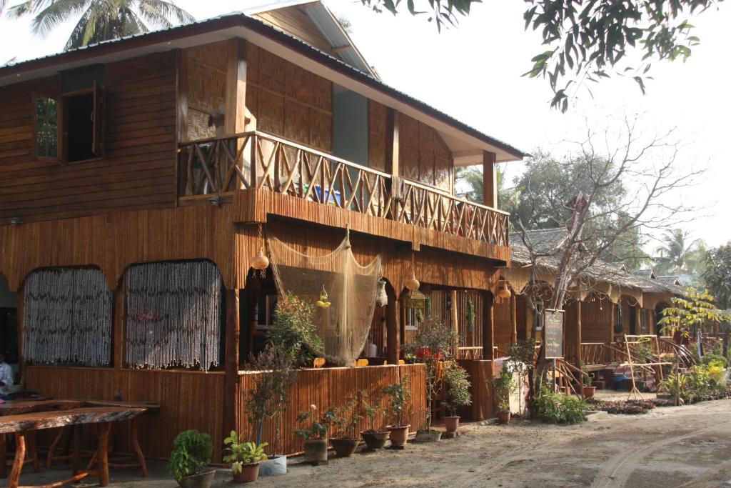 ein Holzhaus mit einem Balkon und Pflanzen darauf in der Unterkunft Soe Ko Ko Beach House & Restaurant in Ngwesaung