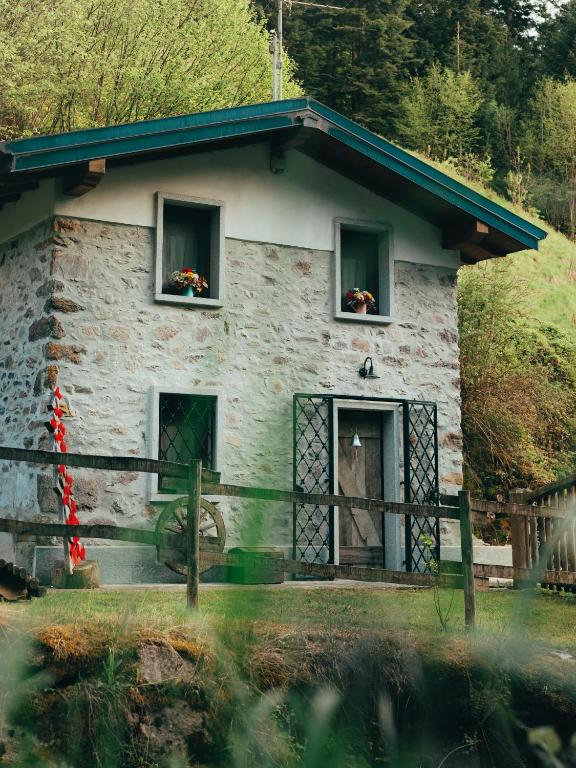 a stone house with two windows and a horse in the doorway at ALLA STALLA Suite & Chalet in Piazzatorre