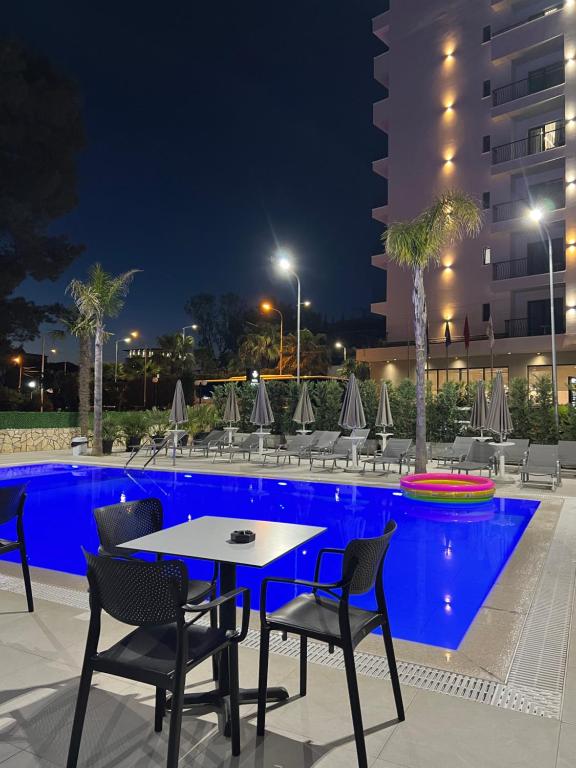 a table and chairs next to a pool at night at Hotel Antik in Golem