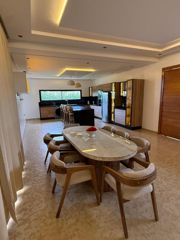 a living room with a table and chairs and a kitchen at Villa 74 Serenety in Heddad
