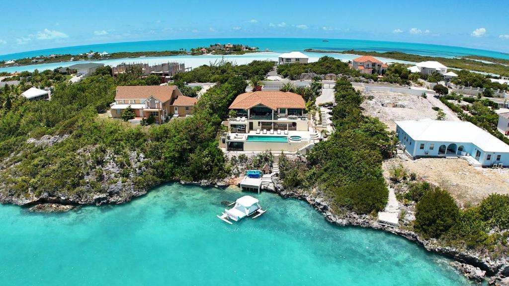 an aerial view of a home with a boat in the water at Alta Bella Villa 8 Bdr Oceanfront Nordic Spa in Providenciales