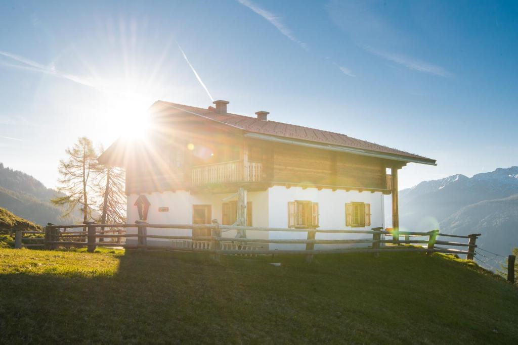 a house on top of a hill with the sun shining at Riggeralm in Rangersdorf
