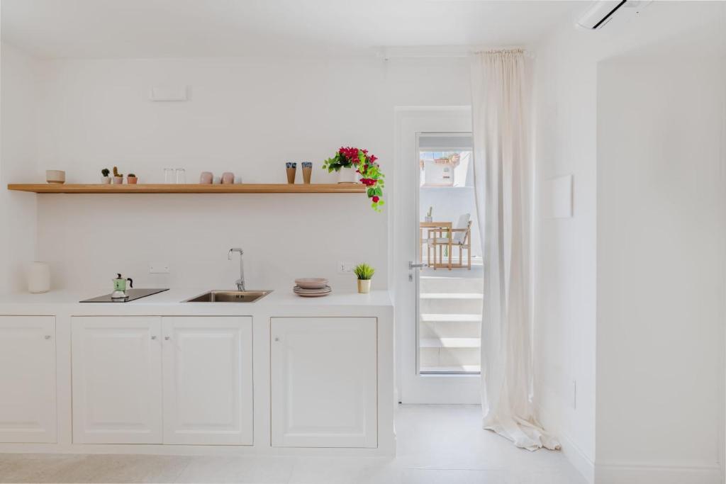 a white kitchen with a sink and a refrigerator at Enea Dimora Procida in Procida