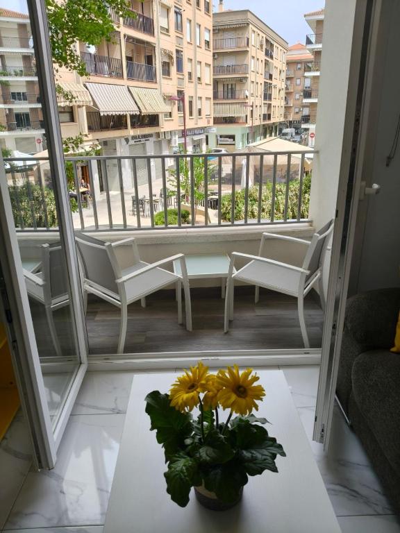 a balcony with a table and a vase with yellow flowers at Apartamentos Dali 1 in Guadix