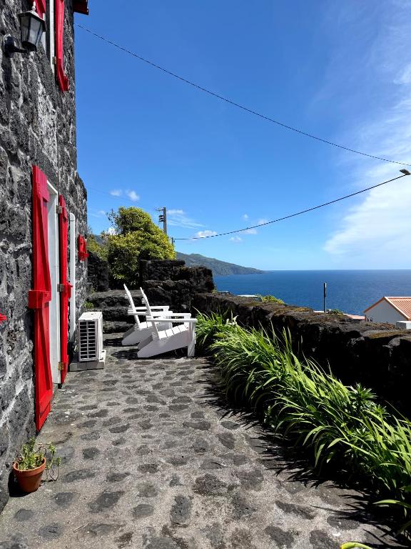 a patio with two white chairs and the ocean at Bruma do Pico House in Lajes do Pico