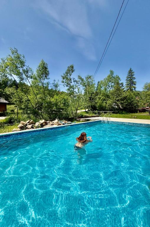 a person swimming in a pool of blue water at Guest House Danver in Yaremche